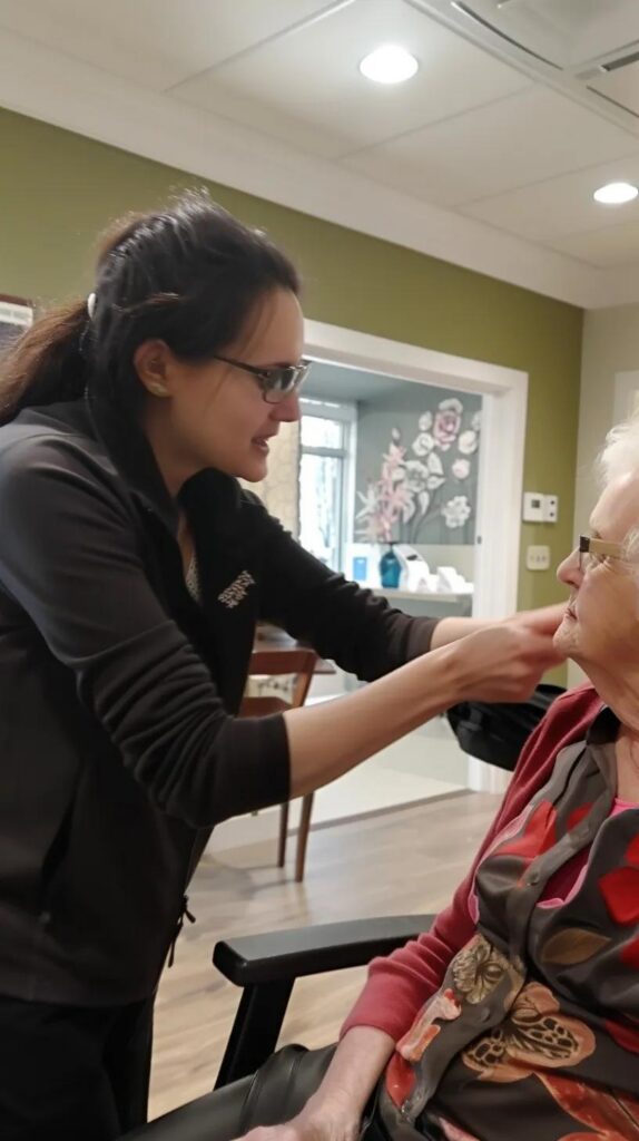 Caregivers using the hand-under-hand technique with a resident, showcasing the Positive Approach to Care methodology