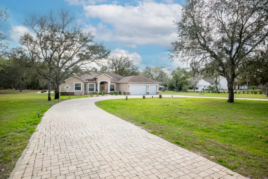 Affordable assisted living facility exterior in Spring Hill, FL, featuring a welcoming entrance, landscaped yard, and paved driveway, surrounded by greenery.